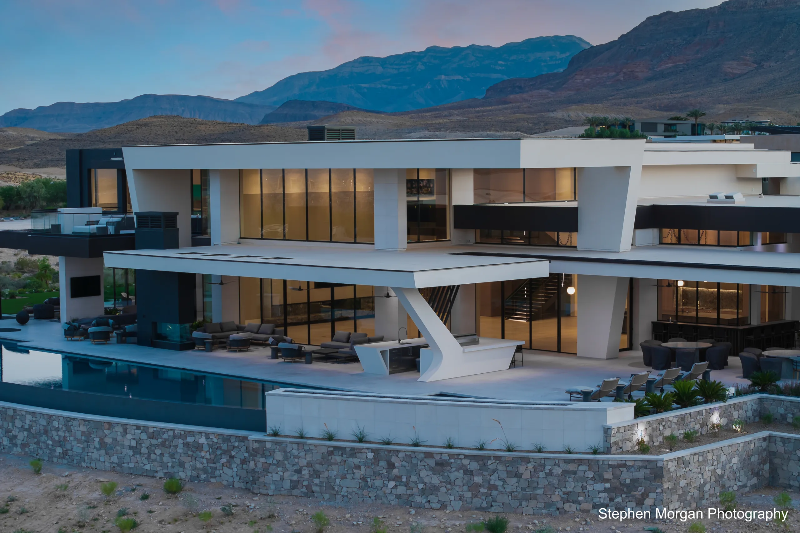 Modern glass-walled luxury estate in Summit Club, Las Vegas, at dusk against the mountains