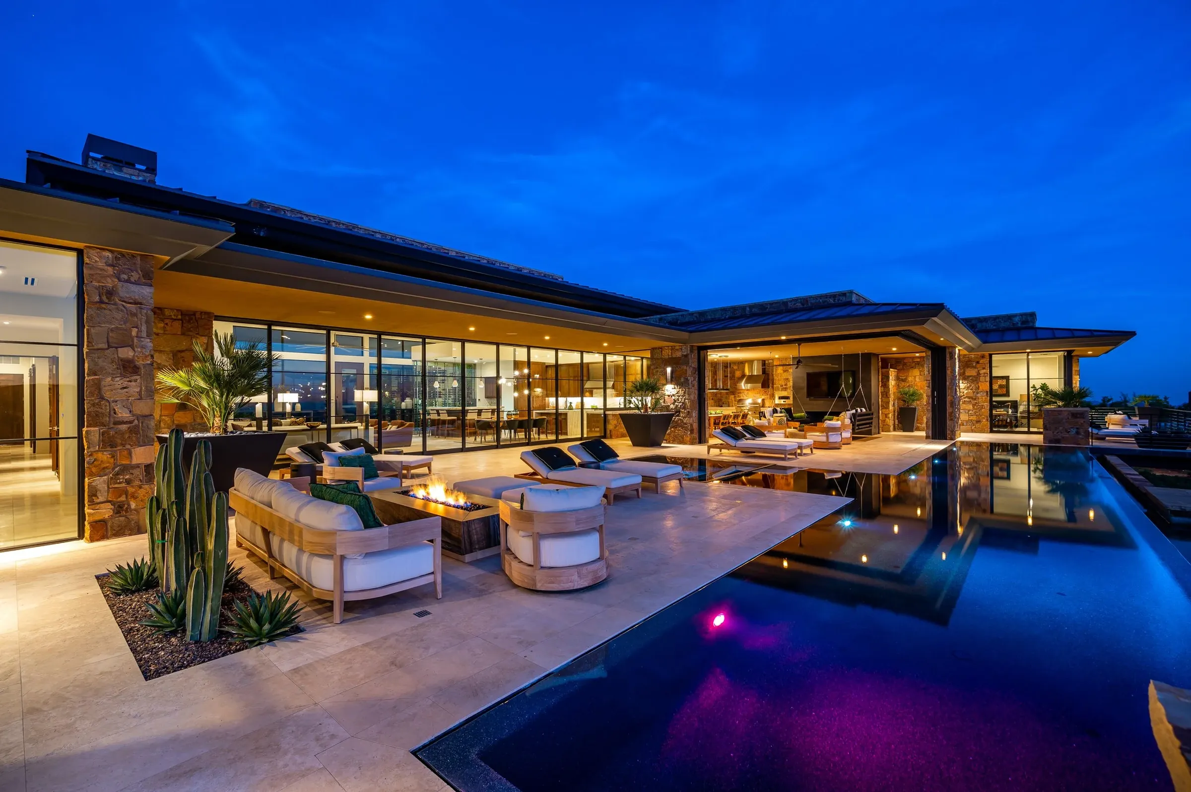 Desert-modern Las Vegas home at dusk with motorized glass walls open to the pool deck